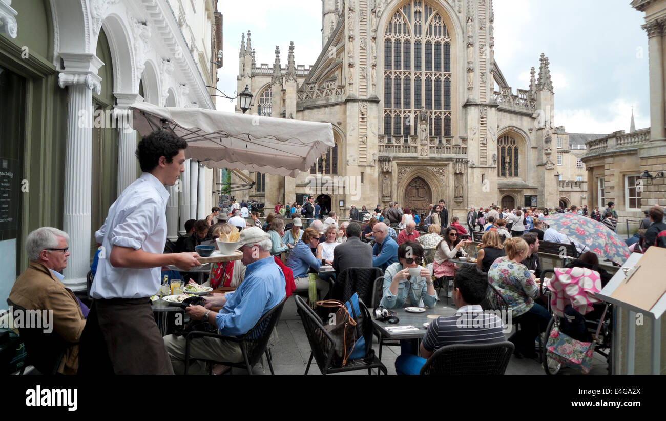 A waiter taking plates of food to customers outside restaurant near