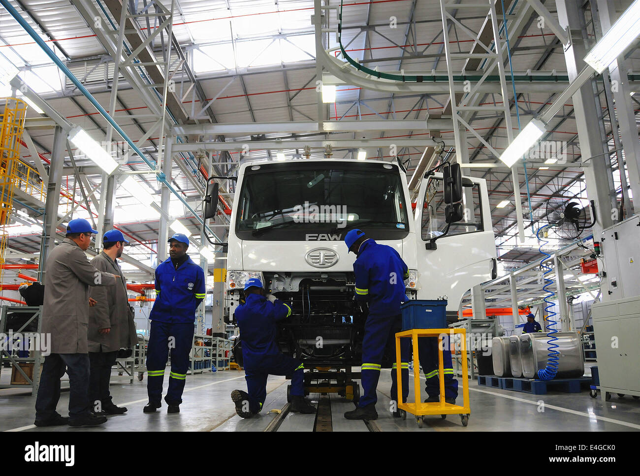 Nelson Mandela, South Africa. 10th July, 2014. Chinese technical personnel and local workers work in new assembly production plant of China First Automotive Works (FAW) Group Corporation in Nelson Mandela Bay Municipality, South Africa, July 10, 2014. China FAW Group Corporation launched its new assembly production plant in COEGA Industrial Development Zone (IDZ) in the Nelson Mandela Bay Municipality on Thursday. The plant, with an investment of 57 million dollars will initially assemble 5,000 trucks annually for the Sub-Saharan African market. © Zhang Chuanshi/Xinhua/Alamy Live News Stock Photo