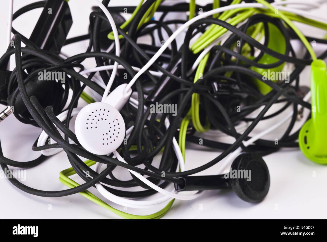 Twisted headphones, of different colors, on white background. Stock Photo