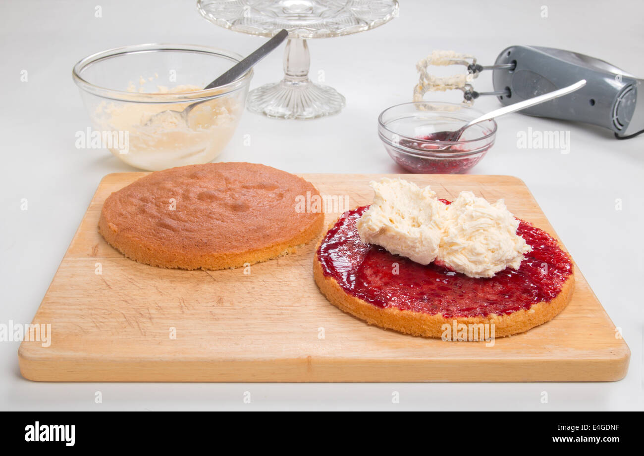 a victoria sponge cake sliced, jam spread, butter cream in place ready for spreading [Land] 'making a cake' (29 of 44) Stock Photo