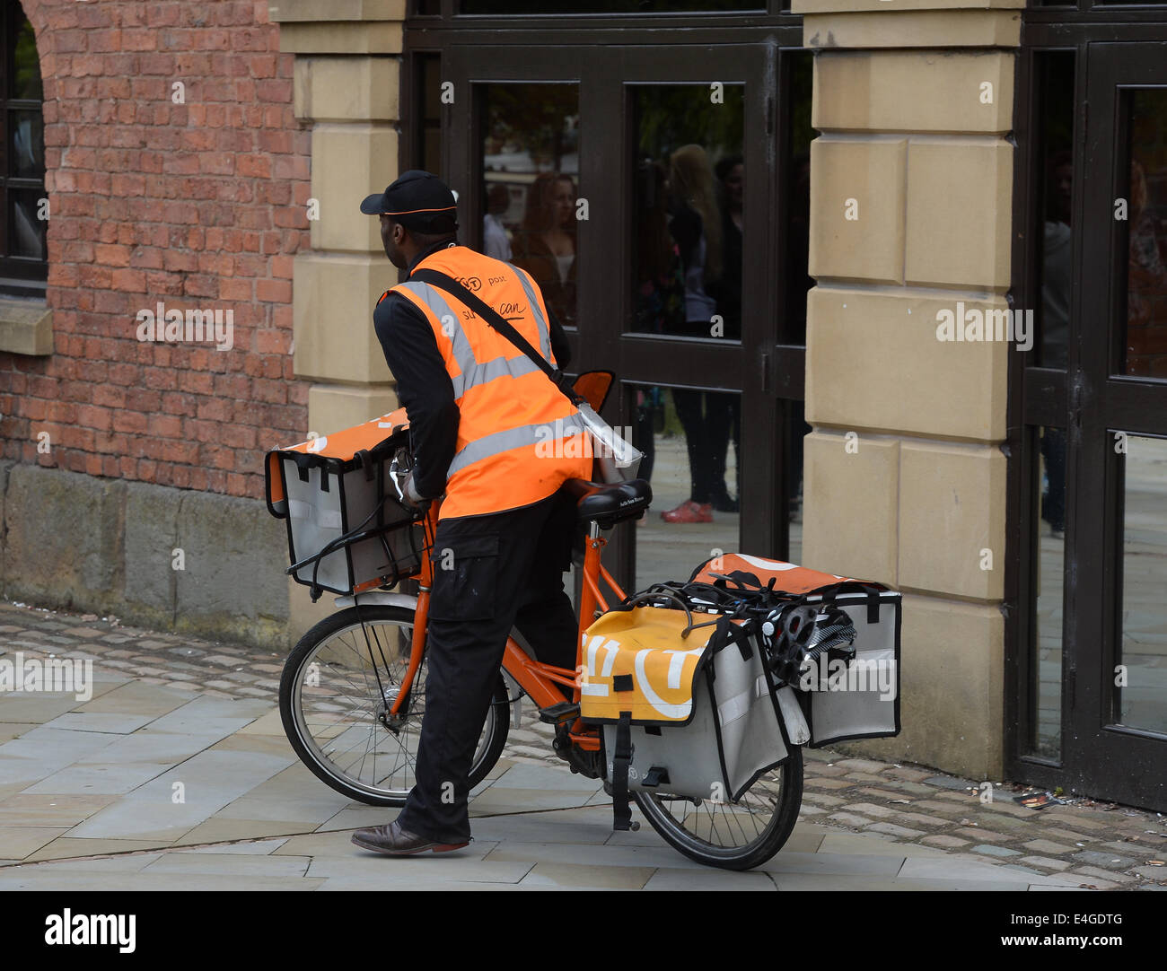 A TNT postman delivers mail to an address in Manchester City Centre, Stock Photo