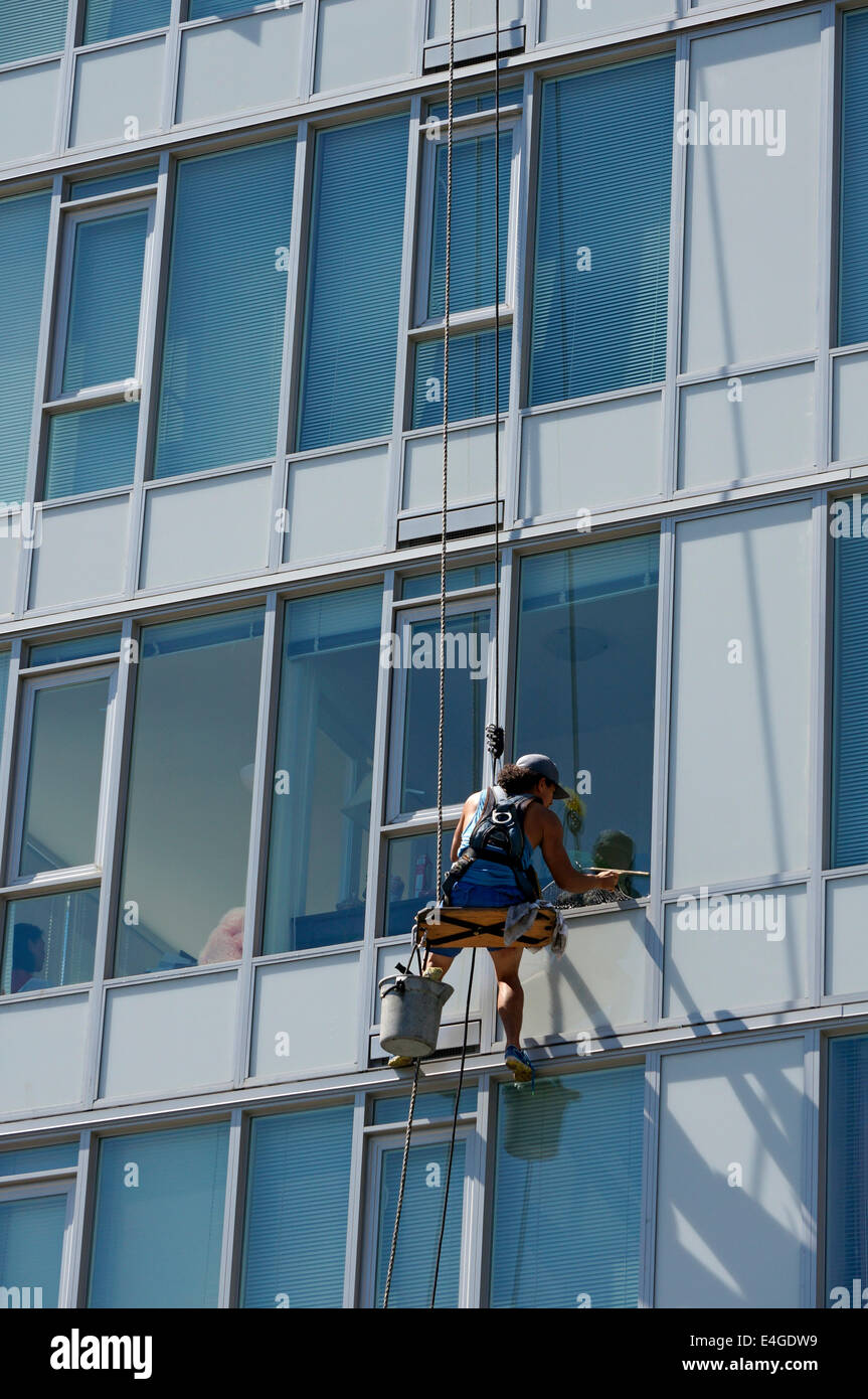 Male window washer cleaning the windows of a glass high rise condominium building in Vancouver, BC, Canada Stock Photo