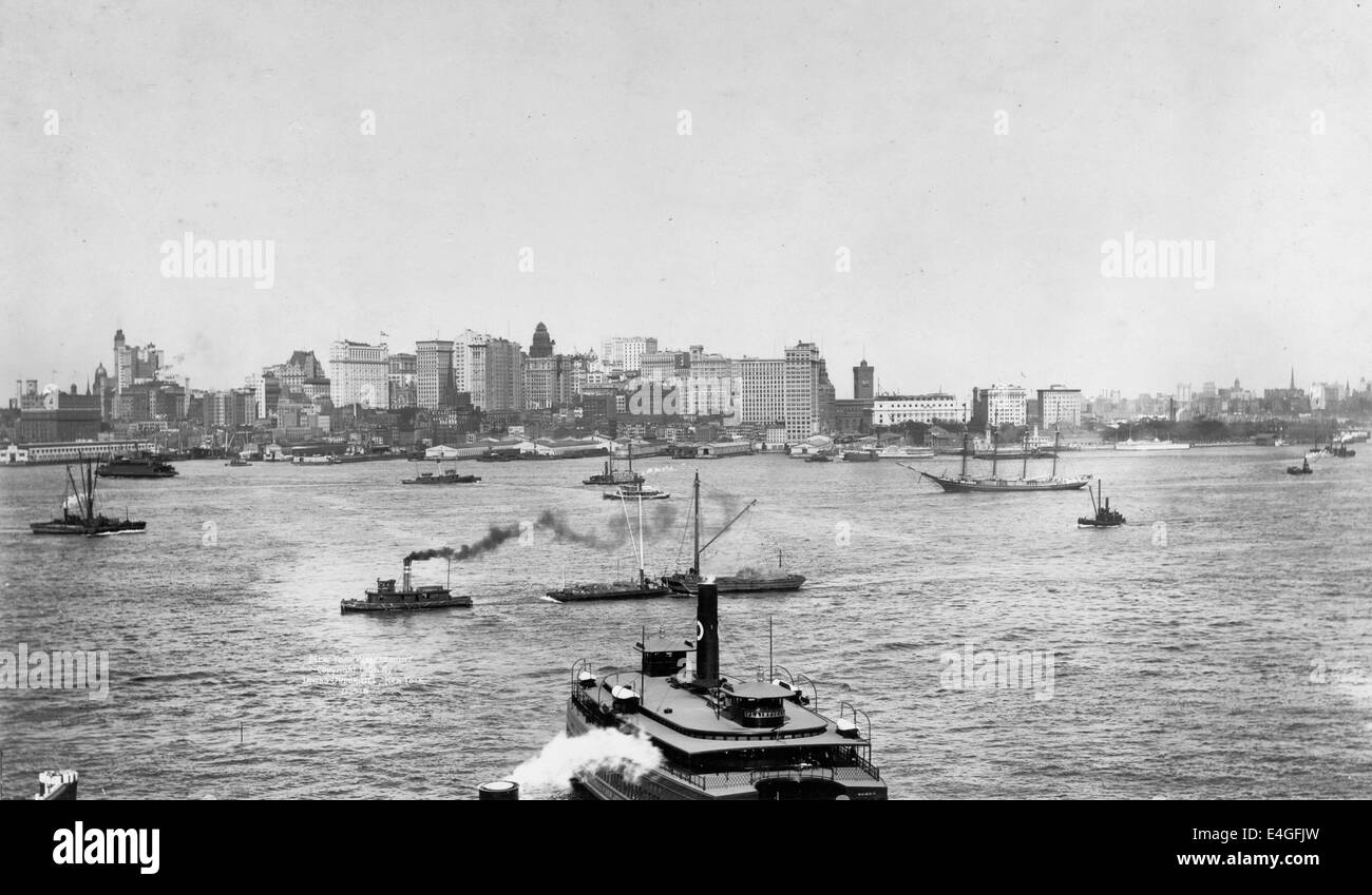 New York Waterfront -  view of the New York City waterfront from across a river, ferry 'Plainfield' in the foreground, tugs and boats in the mid-ground, several 'Pennsylvania Railroad' piers on the waterfront, with tall buildings in the background, circa 1905 Stock Photo