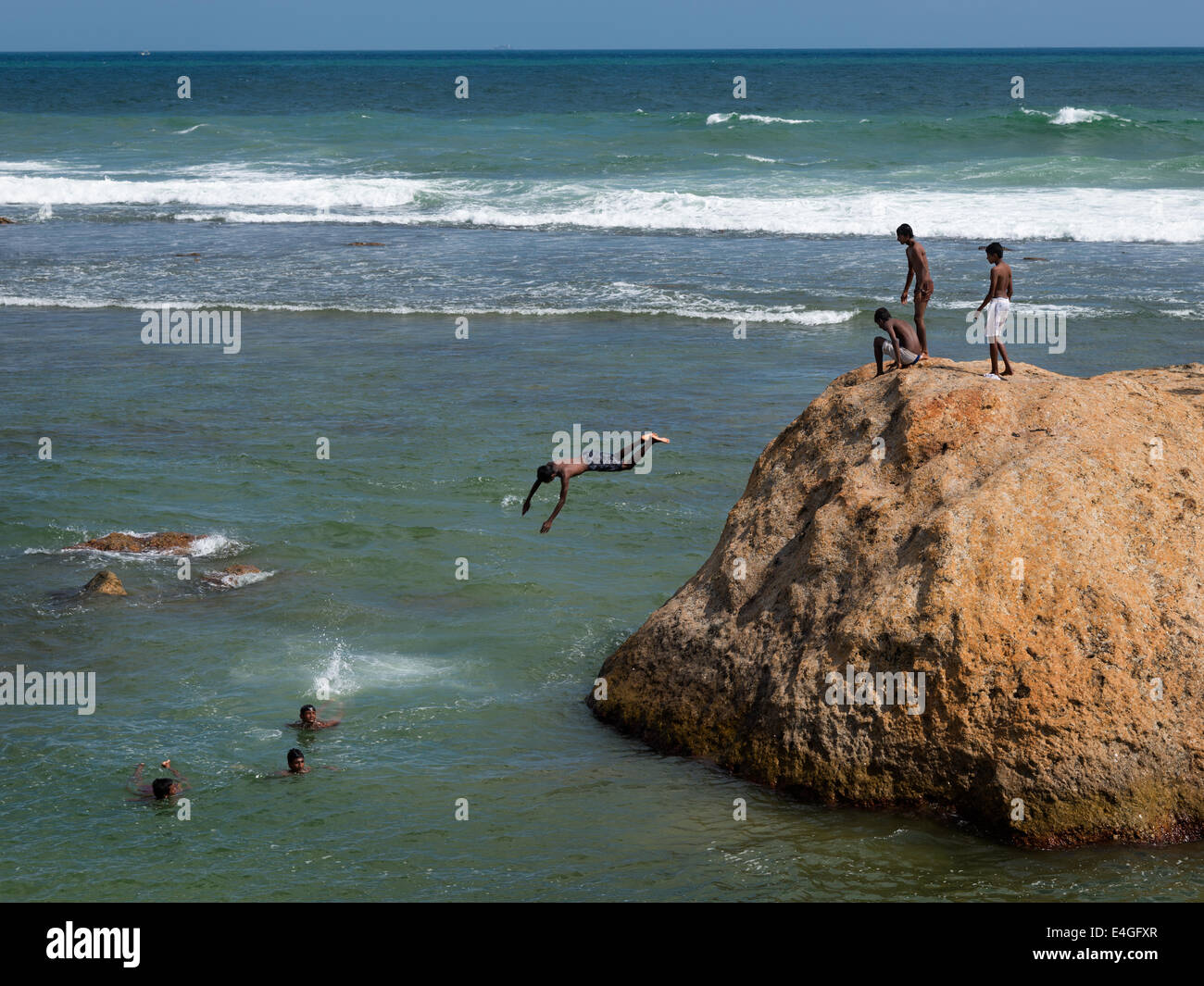 Sri Lankan boys dive into the sea from a large rock in front of the the Fort at Galle, Sri Lanka Stock Photo