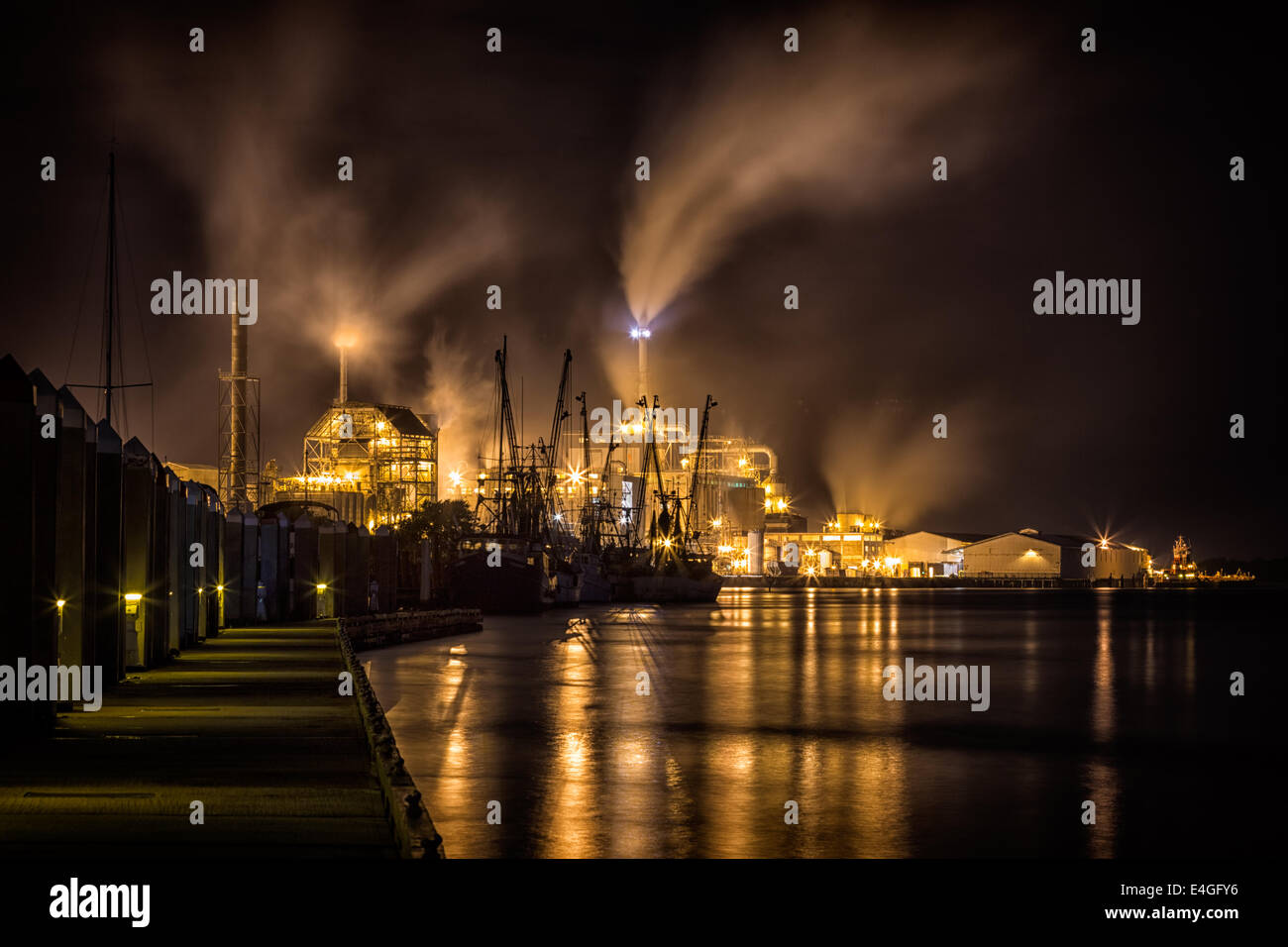 Dramatic night photograph of Fernandina Beach Shrimp Boatssilhouetted by the lights of Rayonier pulp mill on Amelia Island, Flor Stock Photo