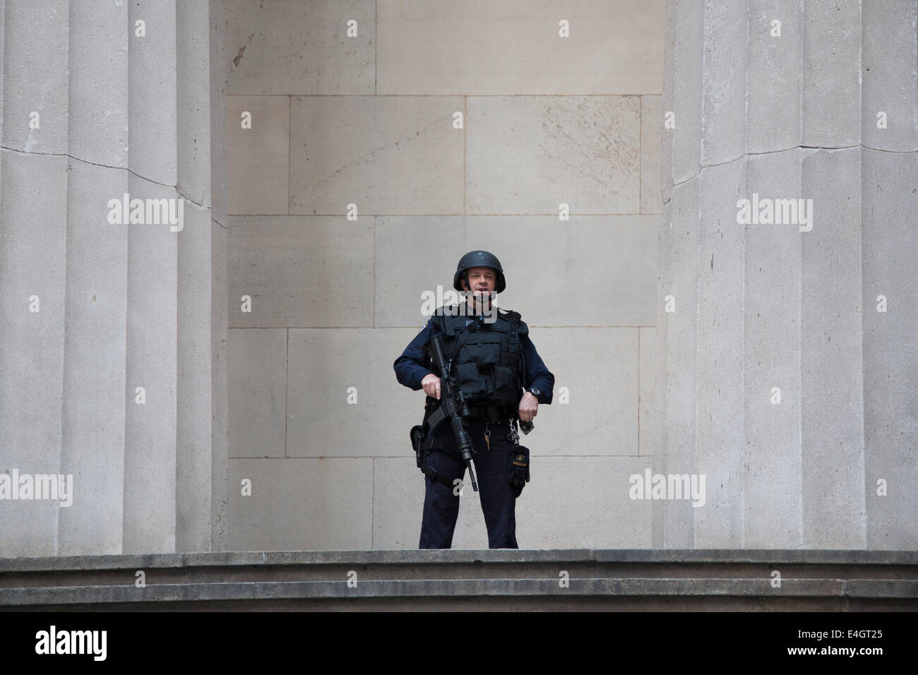 Pillar of the Law USA Police Officer in Full Armour, Federal Hall New York City, Pillars on either side of him. He holds a gun. Stock Photo