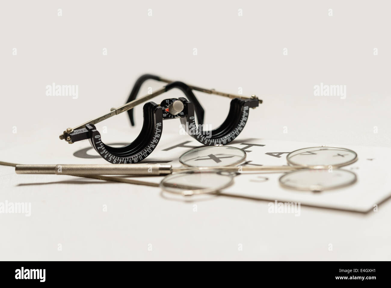 An Oculus half-eye trial frame and binocular twirl confirmation lens lenses on a small Snellen chart. Shallow depth of field. Stock Photo