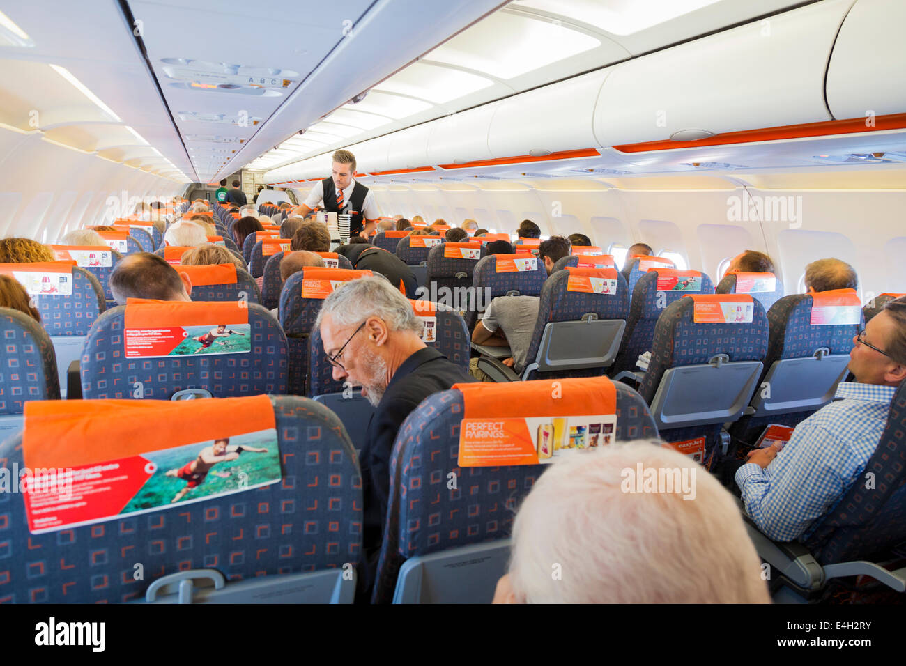 Steward serving passengers in flight in an Easyjet Aircraft. Stock Photo