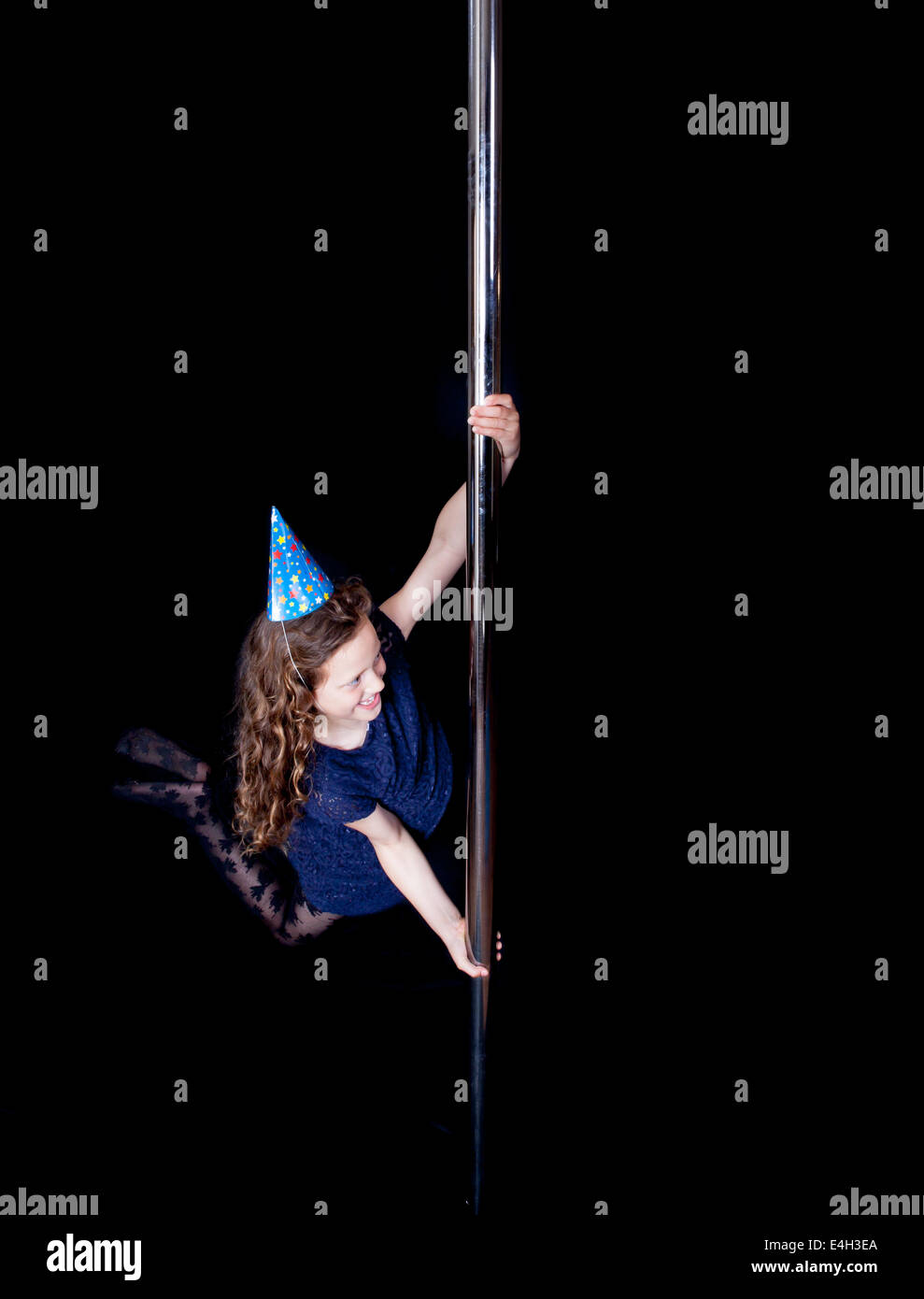 A young girl celebrating her birthday playing on the pole at a pole fitness class. Stock Photo