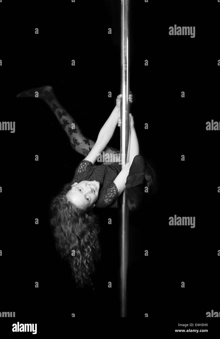 A young girl celebrating her birthday playing on the pole at a pole fitness class. Stock Photo