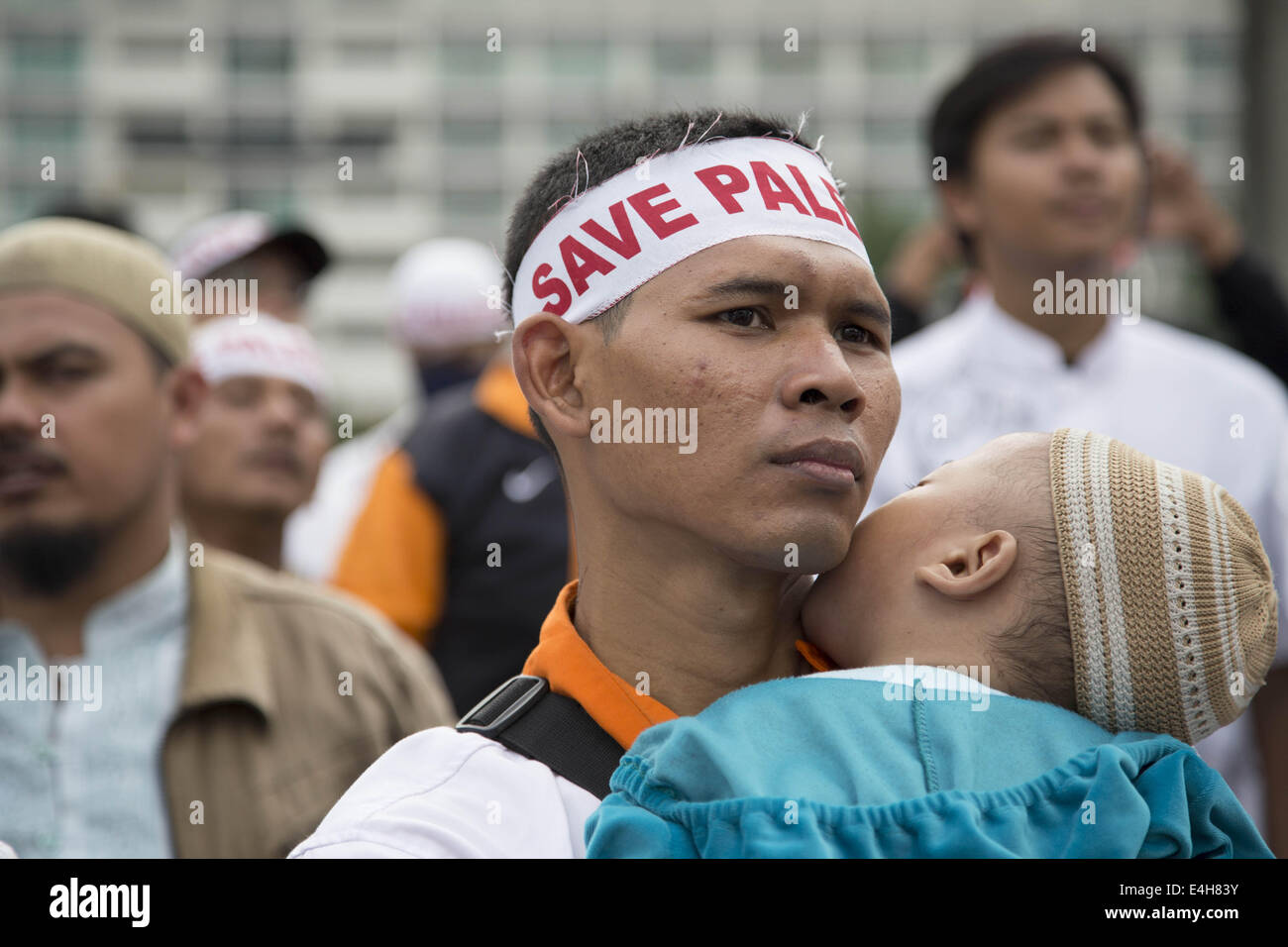 Jakarta, Jakarta, Indonesia. 11th July, 2014. A demonstrant participant with his child. Thousands of Moeslim from all element in Indonesia gathered at Hotel Indonesia Roundabout to protest and condemn the agression of Israel Milliter at Gaza-Palestine that killed almost 70 of Palestine people most are woman and children. Credit:  ZUMA Press, Inc./Alamy Live News Stock Photo