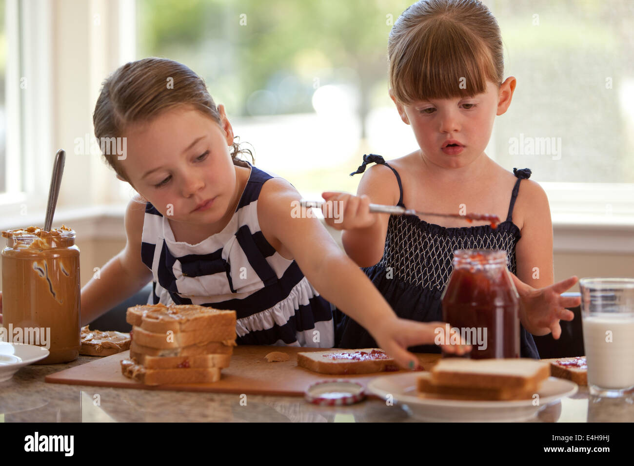 Two Girls Making Sloppy Peanut Butter And Jelly Sandwiches Stock