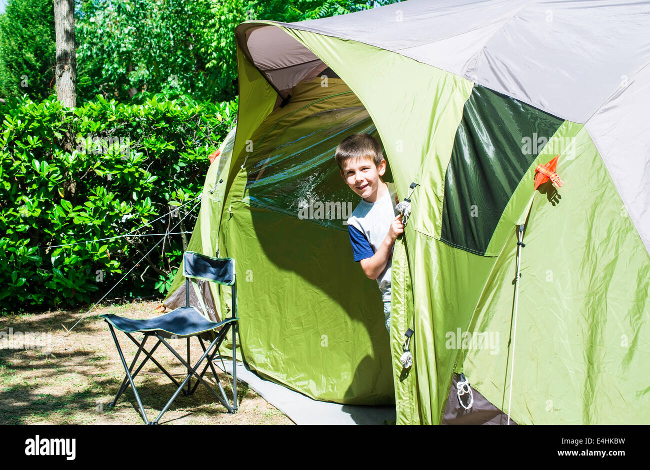 Child peeks from a green tent. Campsite Stock Photo