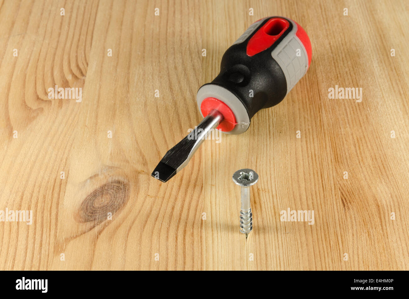 Screw halfway into wood board and a screwdriver Stock Photo Alamy