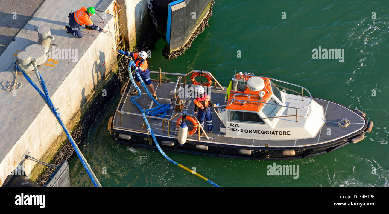 Mooring boat crew assisting large cruise liner to dock by providing hawser  securing services at a cruise ship terminal Stock Photo - Alamy