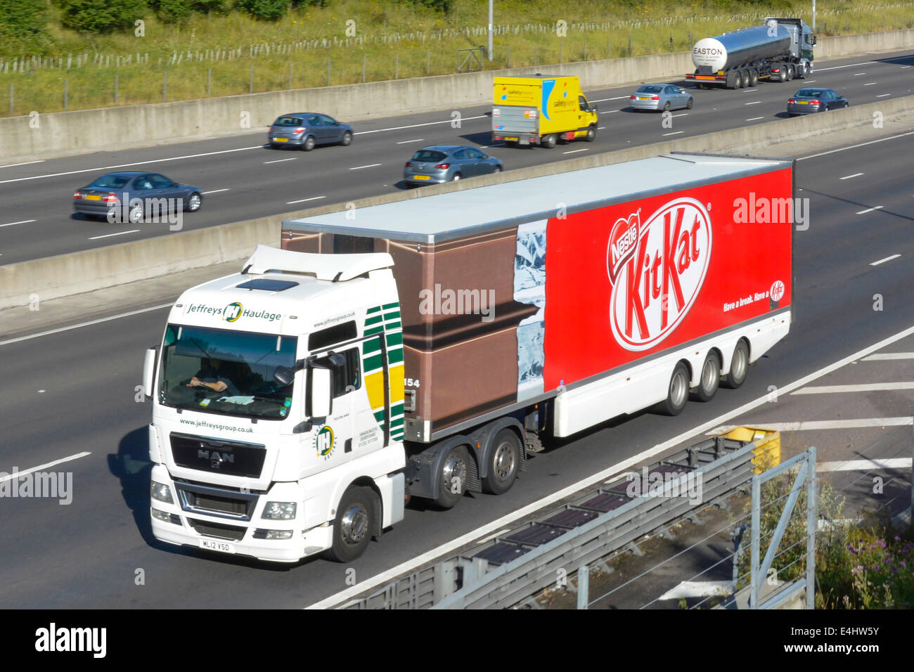 Nestlé Kit Kat chocolate bar & wrapper graphics on side of articulated trailer advertising product behind hgv lorry truck driving along uk  motorway Stock Photo