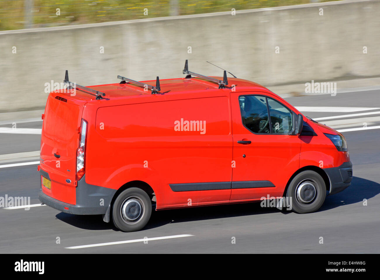 Red Ford Transit van with roof racks at speed on motorway Stock Photo