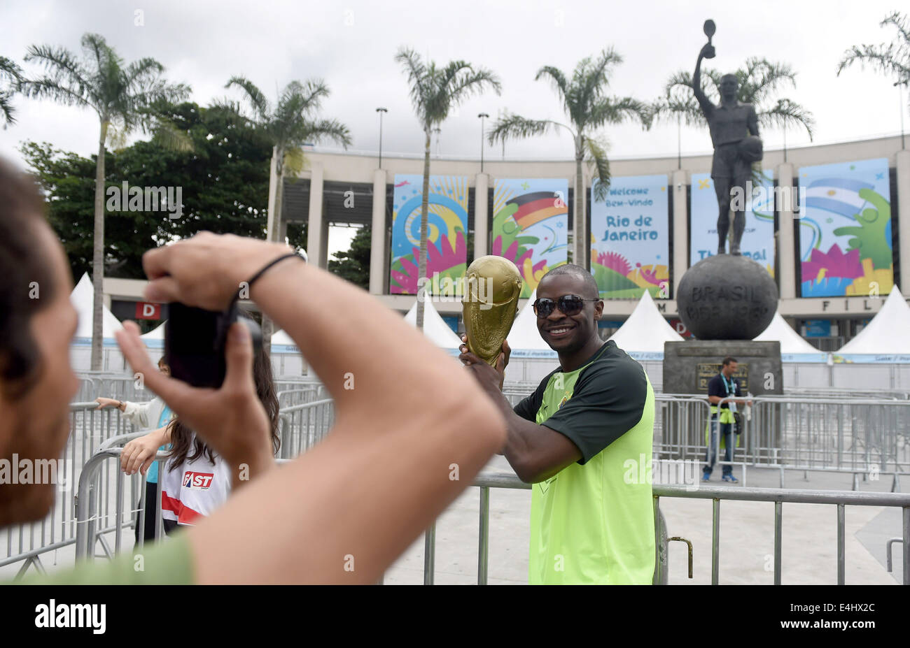 Rio de Janeiro, Brazil. 12th July, 2014. A soccer Fan poses with a copy of the World Cup trophy in front of the Estadio do Maracana in Rio de Janeiro, Brazil, 12 July 2014. Brazil will face The Netherlands on 12 July for the third place in the FIFA World Cup Brazil 2014 match at National Stadium in Brasilia. Photo: Thomas Eisenhuth/dpa/Alamy Live News Stock Photo