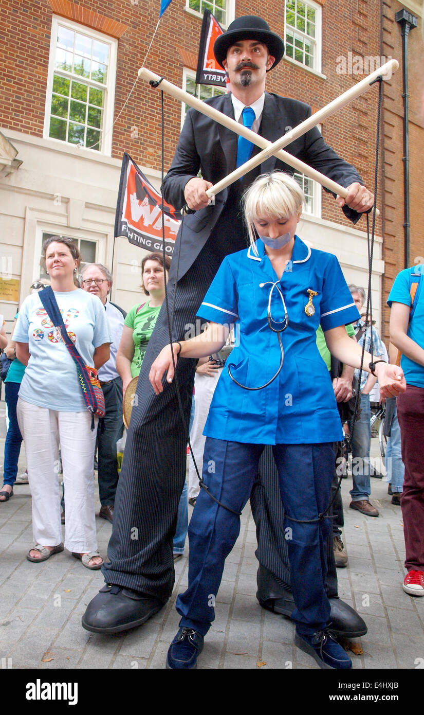 London, UK. 12th July, 2014. A puppet master on stilts pulling the strings of a human NHS nurse puppet gagged with tape during the anti-Transatlantic Trade and Investment Partnership (TTIP) protest in Smith Square Credit:  Mamusu Kallon/Alamy Live News Stock Photo