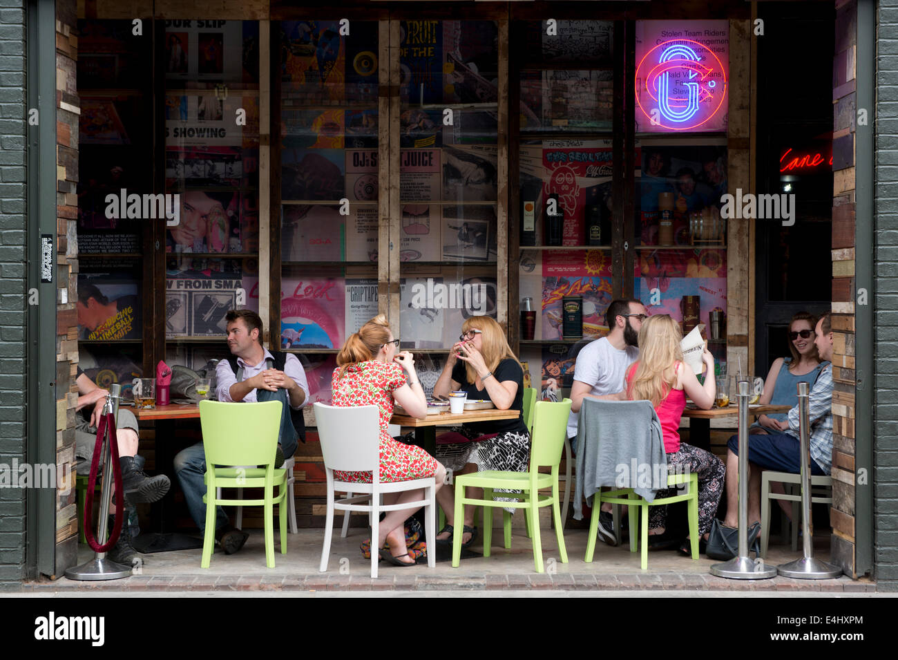 People enjoy the ambiance of a trendy pavement cafe in the bohemian Northern Quarter area of Manchester. Stock Photo