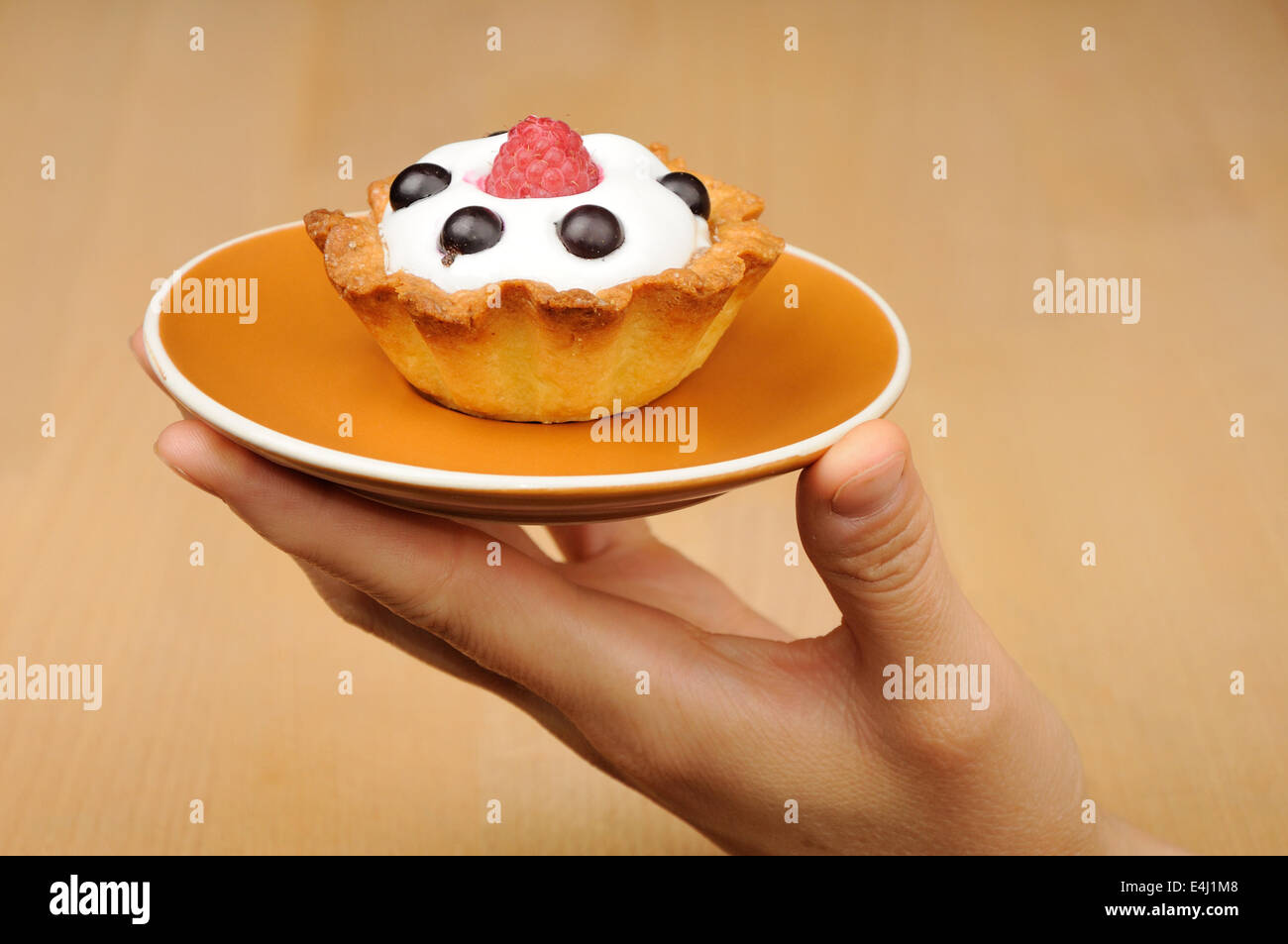 biscuit with cream, raspberry and currant on the plate in woman's hand Stock Photo