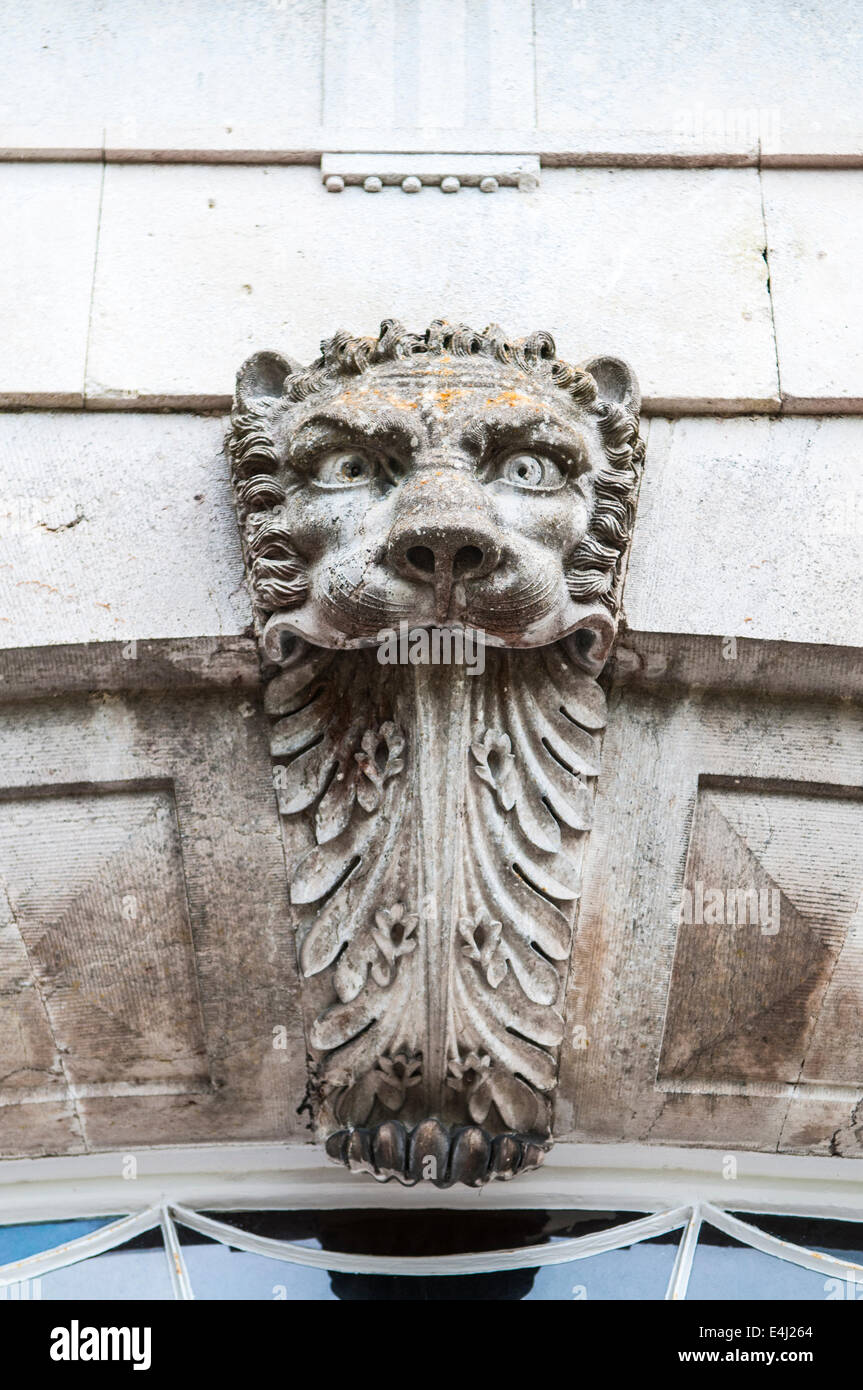 Decal over a door of a carved stone lion's face, with a long tongue. Stock Photo