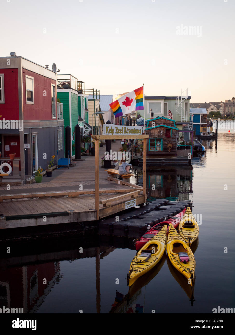 A Canada Gay Pride Flag flies over houseboats and kayaks moored at Fisherman's Wharf in Victoria, British Columbia, Canada. Stock Photo