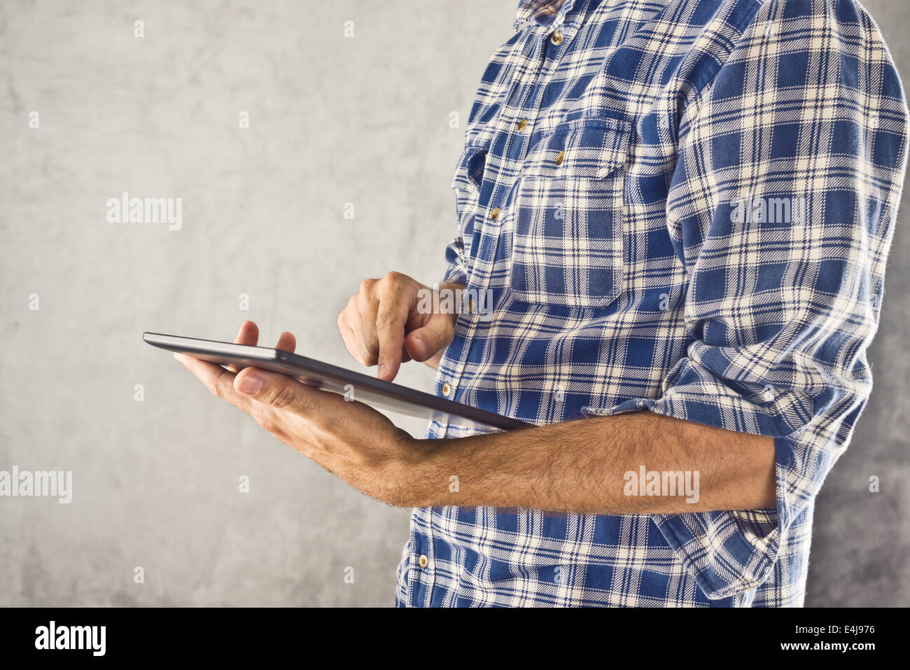 Man holding digital tablet computer and taping the touch screen of modern 10 inch display gadget. Stock Photo