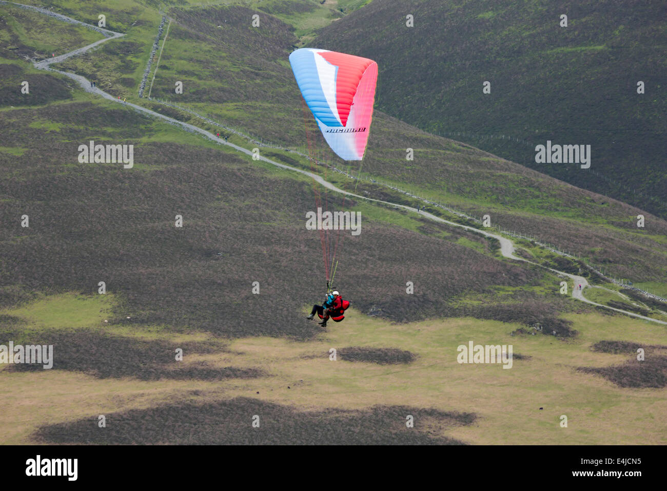 Paragliding lesson in the Lake District, Cumbria. An instructor in tandem with his student flies over the Skiddaw footpath Stock Photo