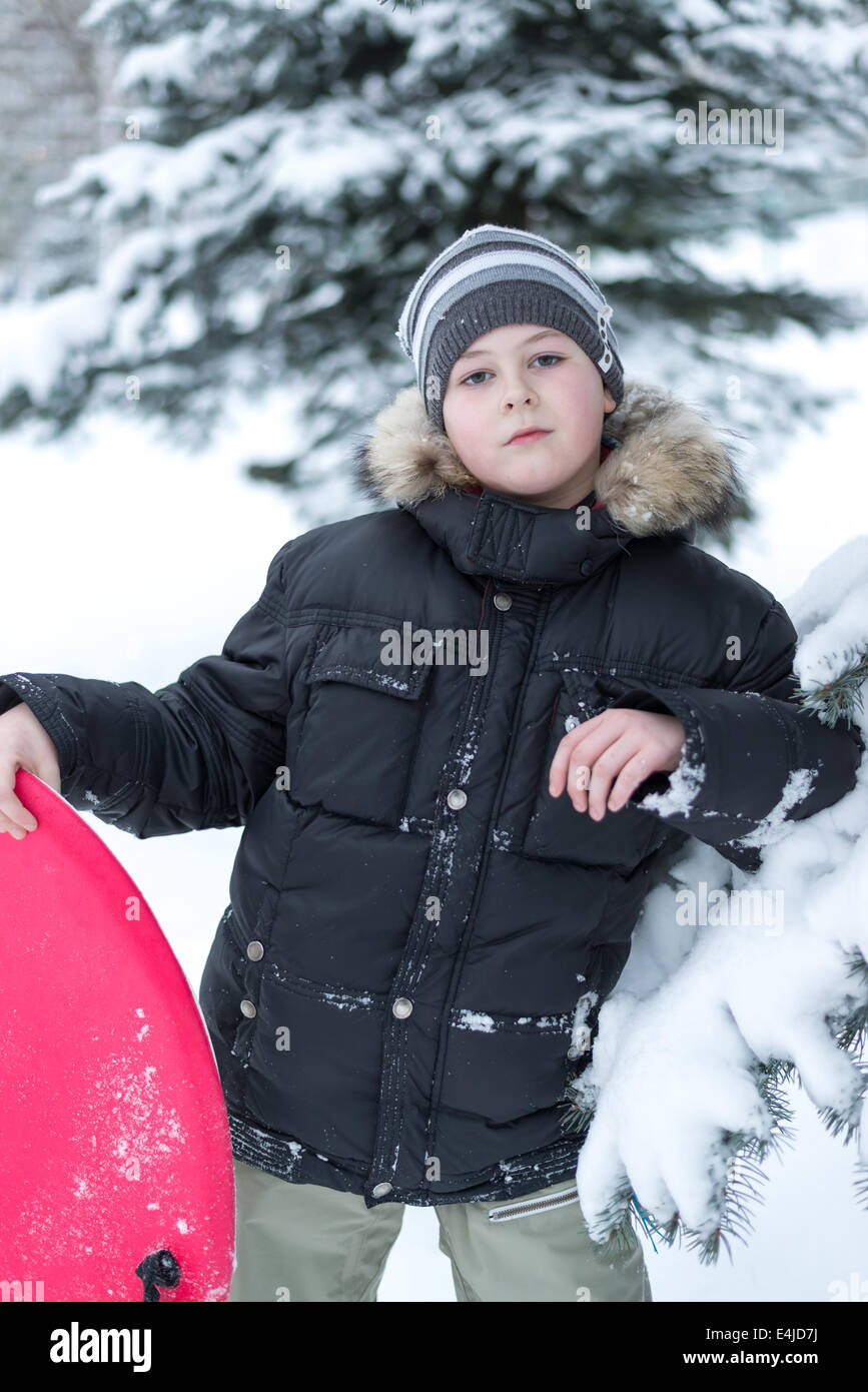 Boy in a snowy forest with a sledge Stock Photo