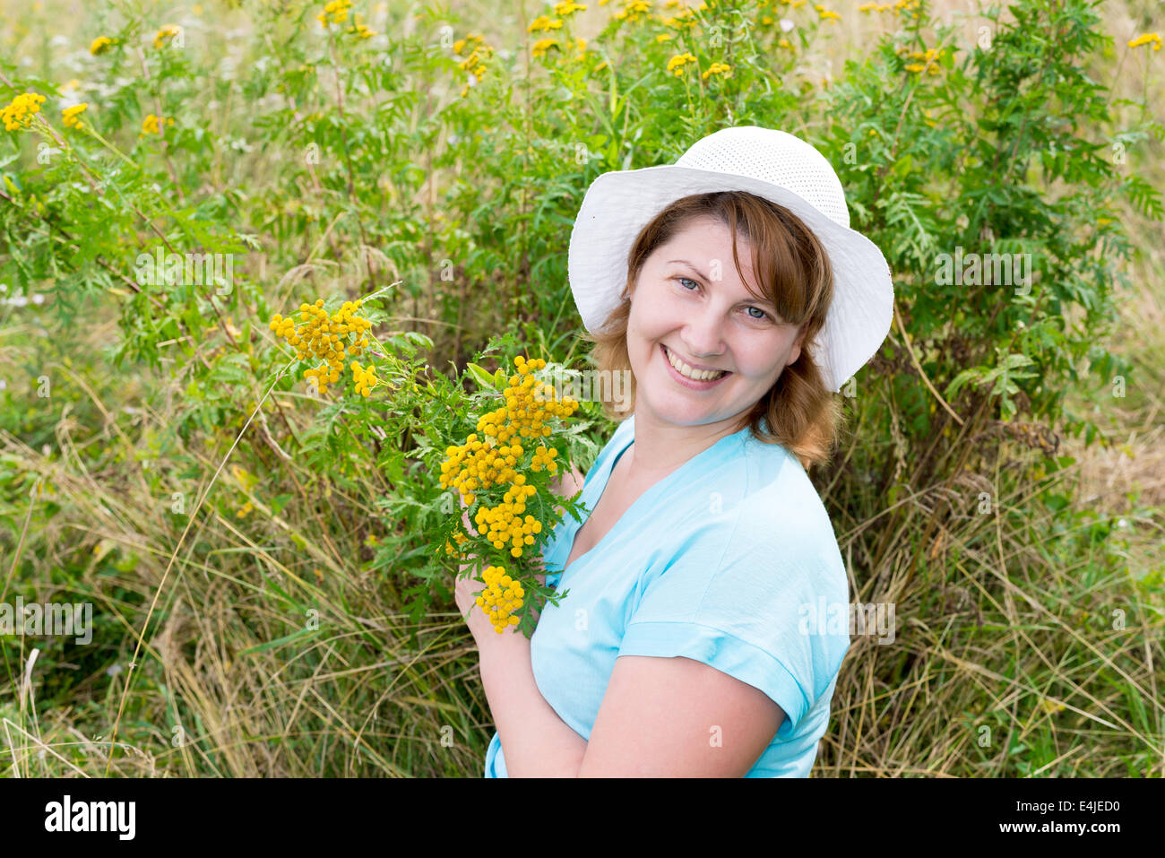 Middle-aged woman on a meadow with tansy Stock Photo