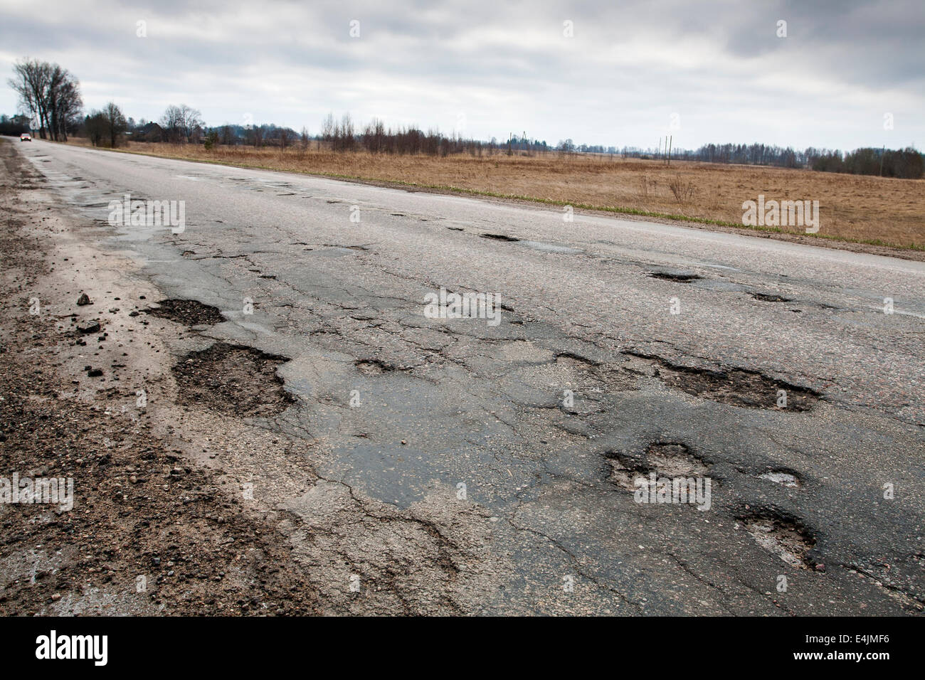 Badly damaged country asphalt road after winter Stock Photo - Alamy