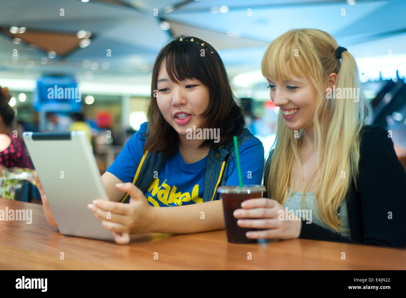 Two young women using digital tablet at a cafe Stock Photo - Alamy