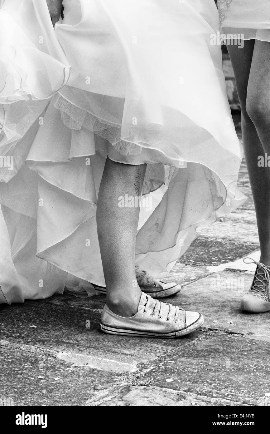 Bride wearing converse trainers for comfort at her wedding Black and White Stock Photo