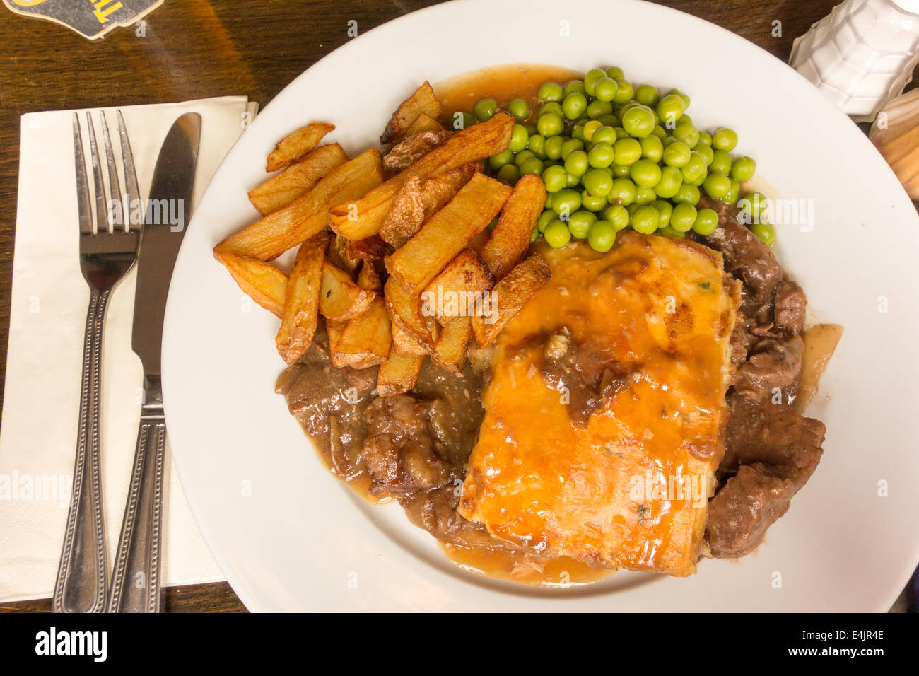 Traditional English pub meal steak pie peas and potato chips and gravy Stock Photo