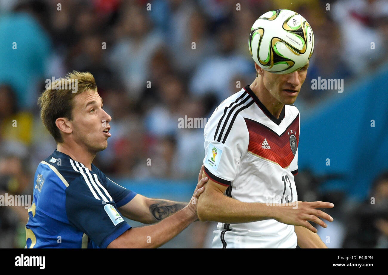 Rio de Janeiro, Brazil. 13th July, 2014. Thomas Mueller of Germany and Lucas Biglia of Argentina vie for the ball during the FIFA World Cup 2014 final soccer match between Germany and Argentina at the Estadio do Maracana in Rio de Janeiro, Brazil, 13 July 2014. Photo: Marcus Brandt/dpa/Alamy Live News Stock Photo