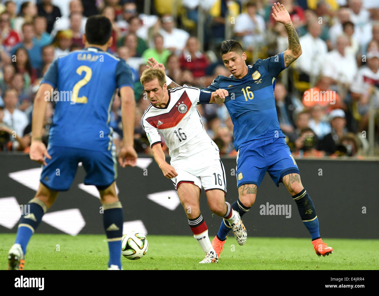 Rio de Janeiro, Brazil. 13th July, 2014. Philipp Lahm (C) of Germany and Ezequiel Garay (L) and Marcos Rojo of Argentina vie for the ball during the FIFA World Cup 2014 final soccer match between Germany and Argentina at the Estadio do Maracana in Rio de Janeiro, Brazil, 13 July 2014. Photo: Andreas Gebert/dpa/Alamy Live News Stock Photo