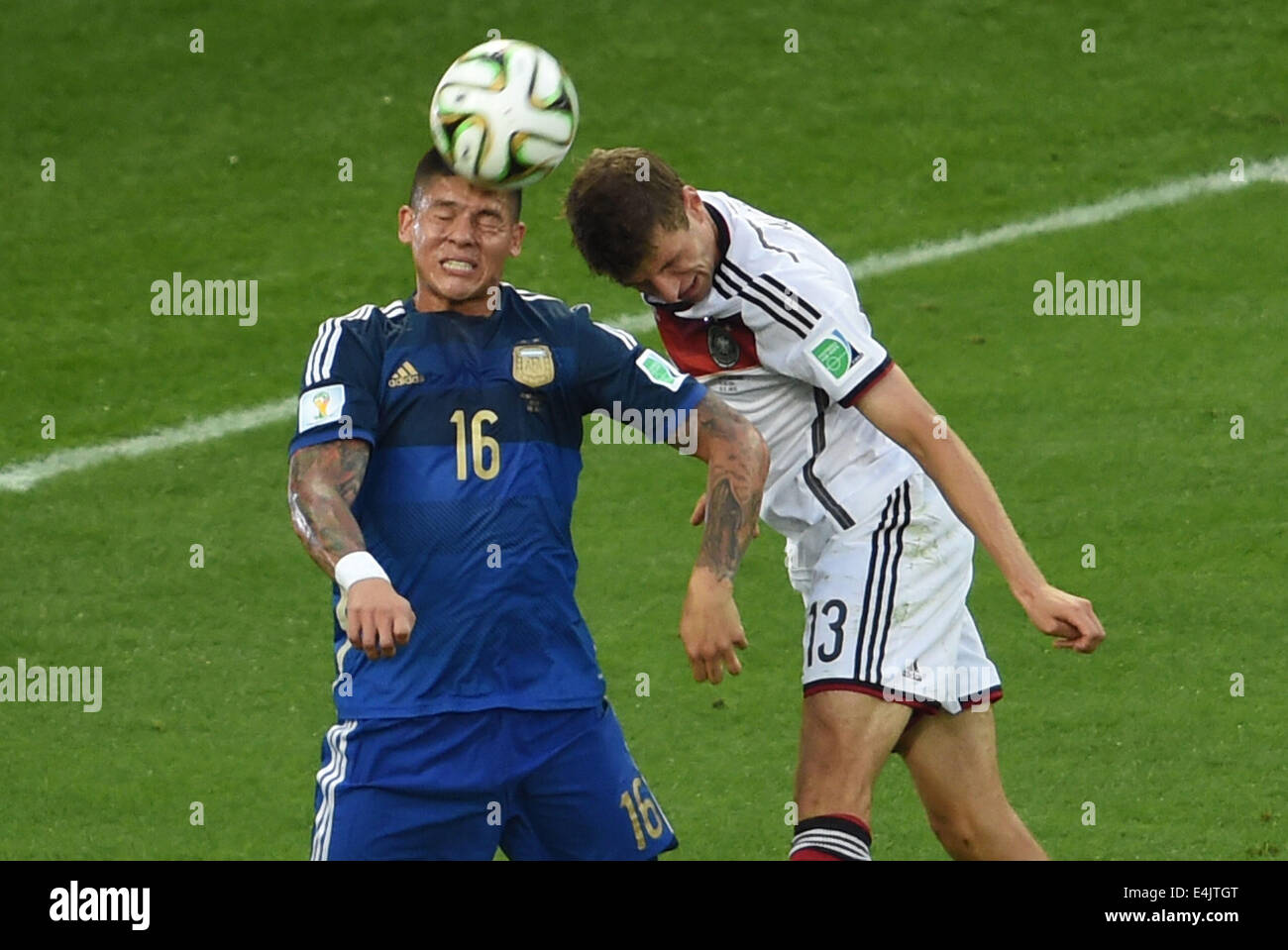 Rio De Janeiro, Brazil. 13th July, 2014. Germany's Thomas Muller competes for a header with Argentina's Marcos Rojo during the final match between Germany and Argentina of 2014 FIFA World Cup at the Estadio do Maracana Stadium in Rio de Janeiro, Brazil, on July 13, 2014. Credit:  Li Ga/Xinhua/Alamy Live News Stock Photo