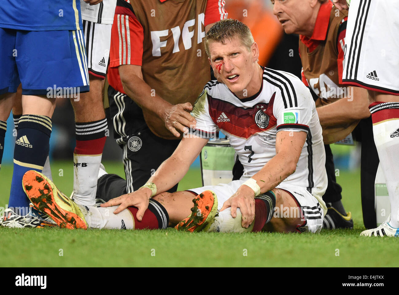 Rio de Janeiro, Brazil. 13th July, 2014. Injured Bastian Schweinsteiger of Germany sits on the ground after being fould by an Argentinian player during the FIFA World Cup 2014 final soccer match between Germany and Argentina at the Estadio do Maracana in Rio de Janeiro, Brazil, 13 July 2014. Photo: Marcus Brandt/dpa/Alamy Live News Stock Photo