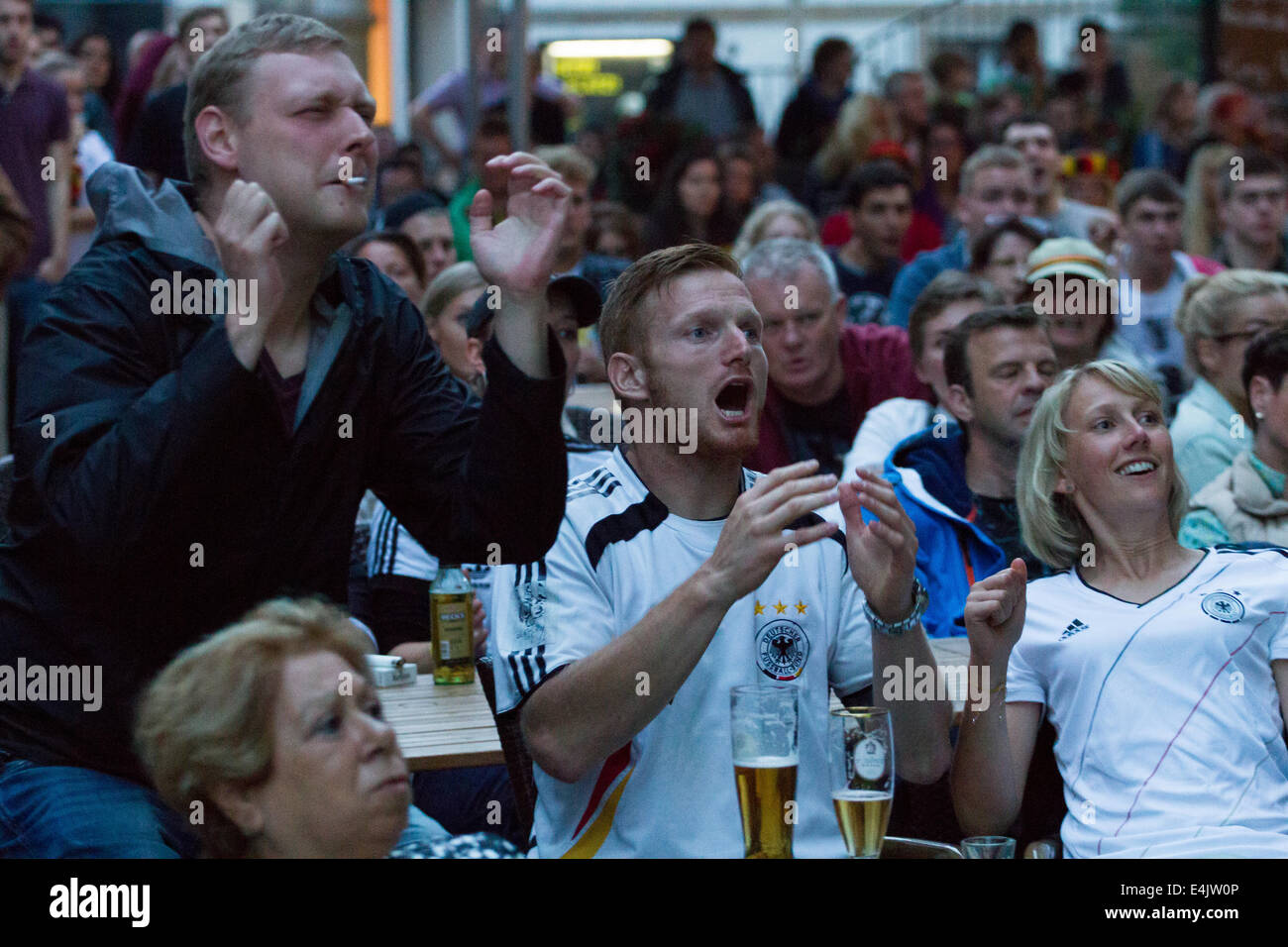 German football fans watch on a large screen outside a cafe as their team come close to scoring. Credit:  Gruffydd Thomas/Alamy Live News Stock Photo