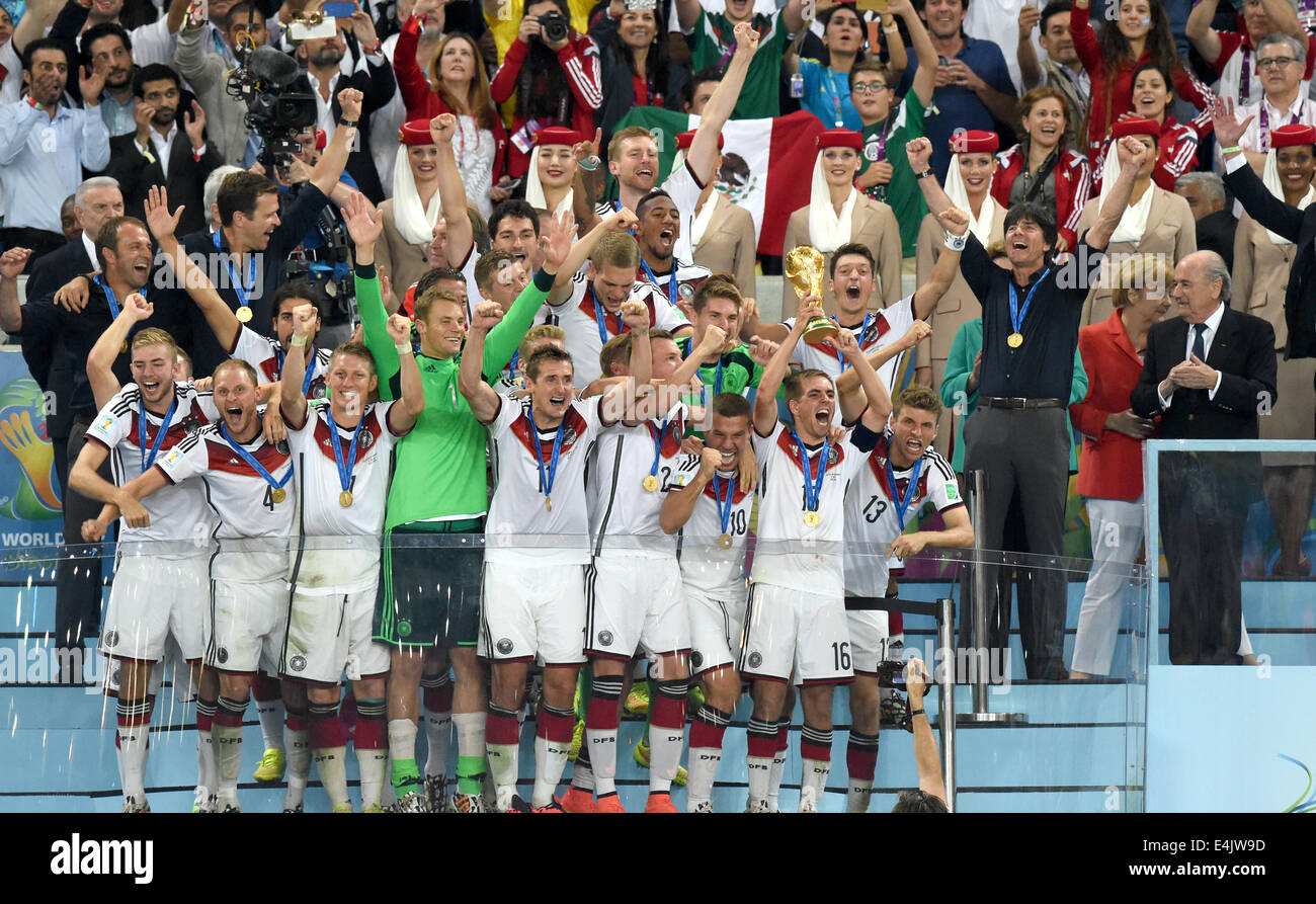 Rio de Janeiro, Brazil. 13th July, 2014. Philipp Lahm (2-R) of Germany lifts up the World Cup trophy with his teammates Lukas Podolski (3-R) and Thomas Mueller (R) and head coach Joachim Loew (2nd row R) and assistant coach Hansi Flick (2nd row L) and team manager Oliver Bierhoff (2nd row 2-L) after winning the FIFA World Cup 2014 final soccer match between Germany and Argentina at the Estadio do Maracana in Rio de Janeiro, Brazil, 13 July 2014. Photo: Marcus Brandt/dpa/Alamy Live News Stock Photo