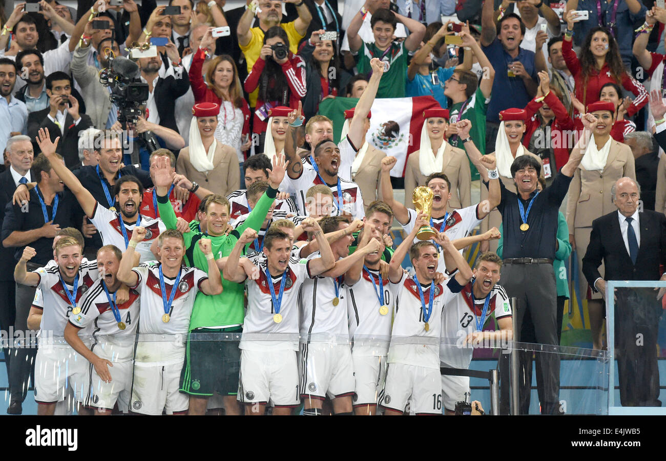 Rio de Janeiro, Brazil. 13th July, 2014. Philipp Lahm (2-R) of Germany lifts up the World Cup trophy with his teammates Lukas Podolski (3-R) and Thomas Mueller (R) and head coach Joachim Loew (2nd row 2-R) and FIFA President Joseph Sepp Blatter (2nd row R) and assistant coach Hansi Flick (2nd row L) and team manager Oliver Bierhoff (2nd row 2-L) after winning the FIFA World Cup 2014 final soccer match between Germany and Argentina at the Estadio do Maracana in Rio de Janeiro, Brazil, 13 July 2014. Photo: Marcus Brandt/dpa/Alamy Live News Stock Photo