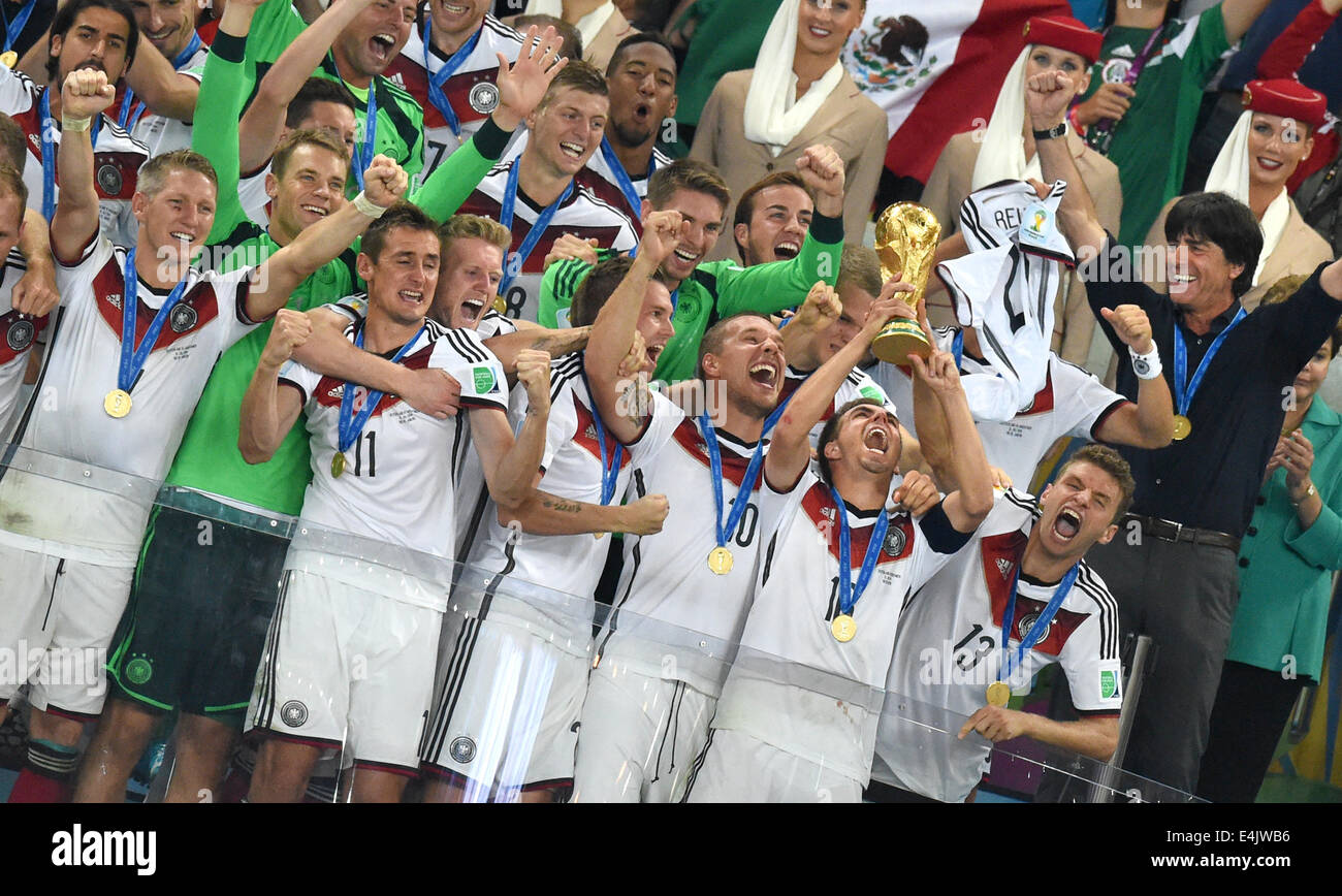 Rio de Janeiro, Brazil. 13th July, 2014. Philipp Lahm (2-R) of Germany lifts up the World Cup trophy between his teammates Lukas Podolski (3-R) and Thomas Mueller (R) and head coach Joachim Loew (2nd row R) and Mario Goetze (C top) after winning the FIFA World Cup 2014 final soccer match between Germany and Argentina at the Estadio do Maracana in Rio de Janeiro, Brazil, 13 July 2014. Photo: Marcus Brandt/dpa/Alamy Live News Stock Photo