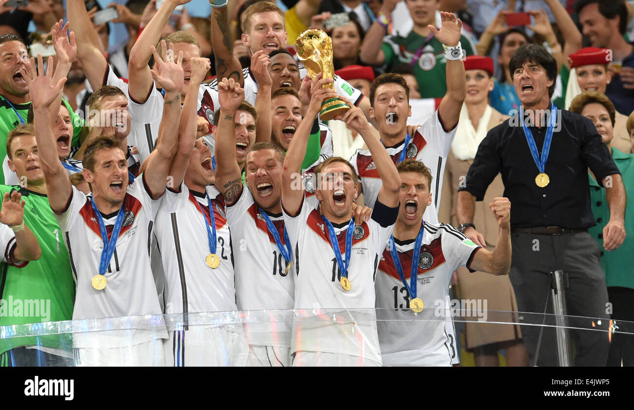 Rio de Janeiro, Brazil. 13th July, 2014. Philipp Lahm (C) of Germany lifts up the World Cup trophy between his teammates goalkeeper Manuel Neuer (first row L-R), Miroslav Klose Kevin Großkreutz, Lukas Podolski and Thomas Mueller; Headcoach Joachim Loew of Germany (second row R-L), Mesut Oezil and Mario Goetze after winning the FIFA World Cup 2014 final soccer match between Germany and Argentina at the Estadio do Maracana in Rio de Janeiro, Brazil, 13 July 2014. Photo:Andreas Gebert/dpa/Alamy Live News Stock Photo