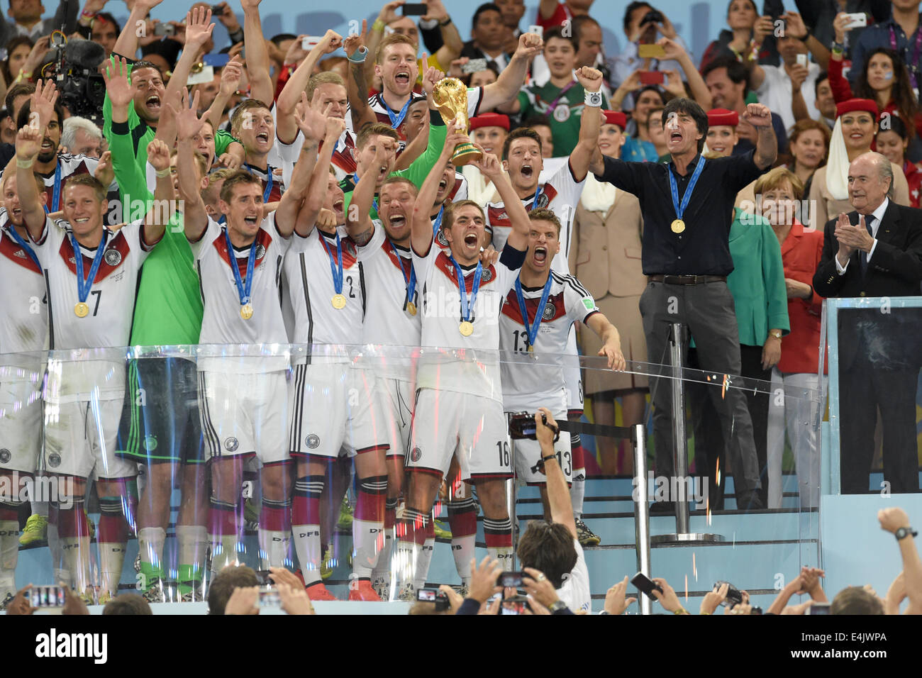 Rio de Janeiro, Brazil. 13th July, 2014. Philipp Lahm (C) of Germany lifts up the World Cup trophy between his teammates Bastian Schweinsteiger (first row L-R), goalkeeper Manuel Neuer Miroslav Klose, Kevin Großkreutz, Lukas Podolski and Thomas Mueller; Headcoach Joachim Loew of Germany (second row R-L) and Mesut Oezil after winning the FIFA World Cup 2014 final soccer match between Germany and Argentina at the Estadio do Maracana in Rio de Janeiro, Brazil, 13 July 2014. Photo:Andreas Gebert/dpa/Alamy Live News Stock Photo