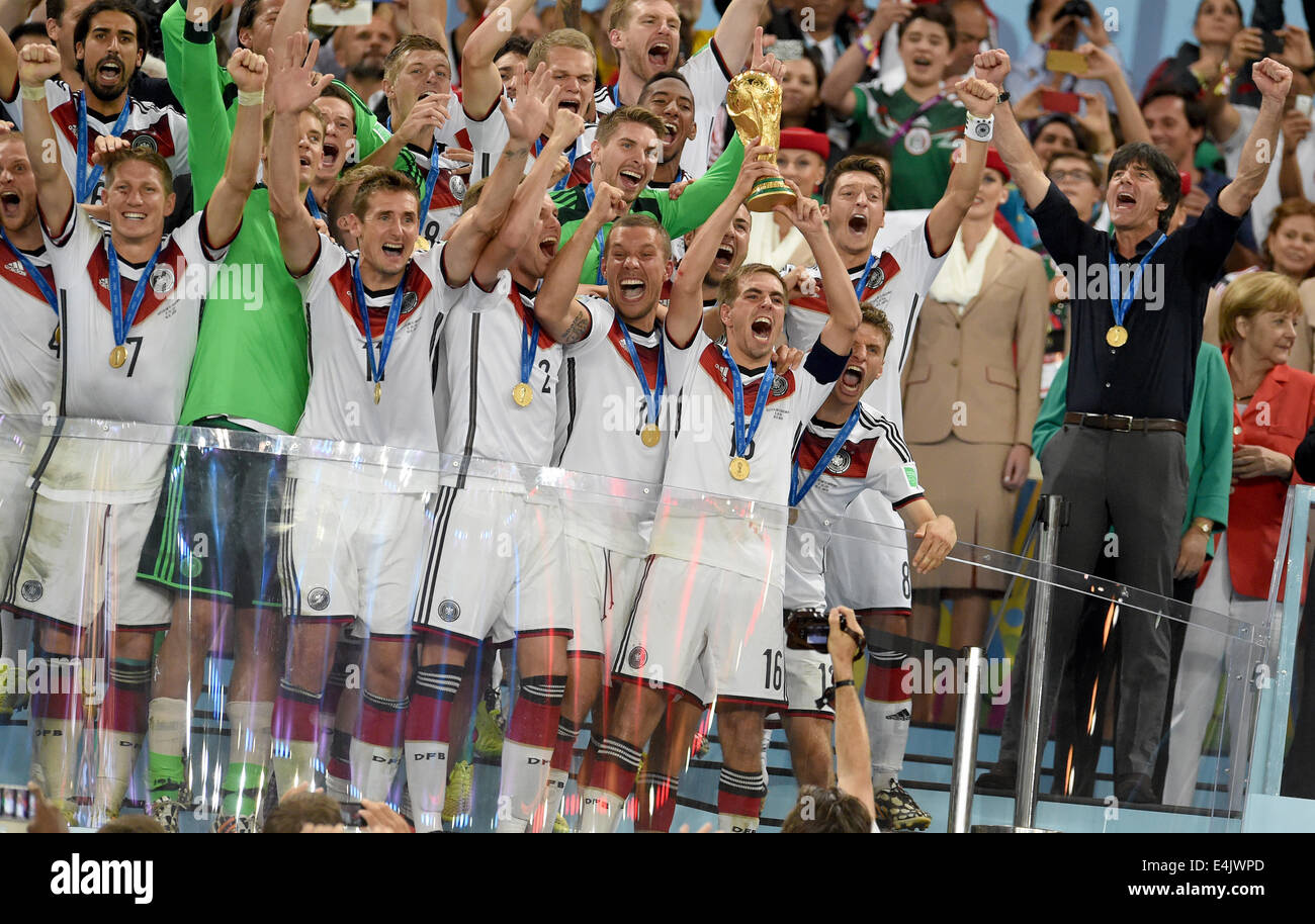 Rio de Janeiro, Brazil. 13th July, 2014. Philipp Lahm (C) of Germany lifts up the World Cup trophy between his teammates Bastian Schweinsteiger (first row L-R), goalkeeper Manuel Neuer Miroslav Klose, Kevin Großkreutz, Lukas Podolski and Thomas Mueller; Headcoach Joachim Loew of Germany (second row R-L), Mesut Oezil and MArio Goetze (partly hidden) after winning the FIFA World Cup 2014 final soccer match between Germany and Argentina at the Estadio do Maracana in Rio de Janeiro, Brazil, 13 July 2014. Photo: Andreas Gebert/dpa/Alamy Live News Stock Photo