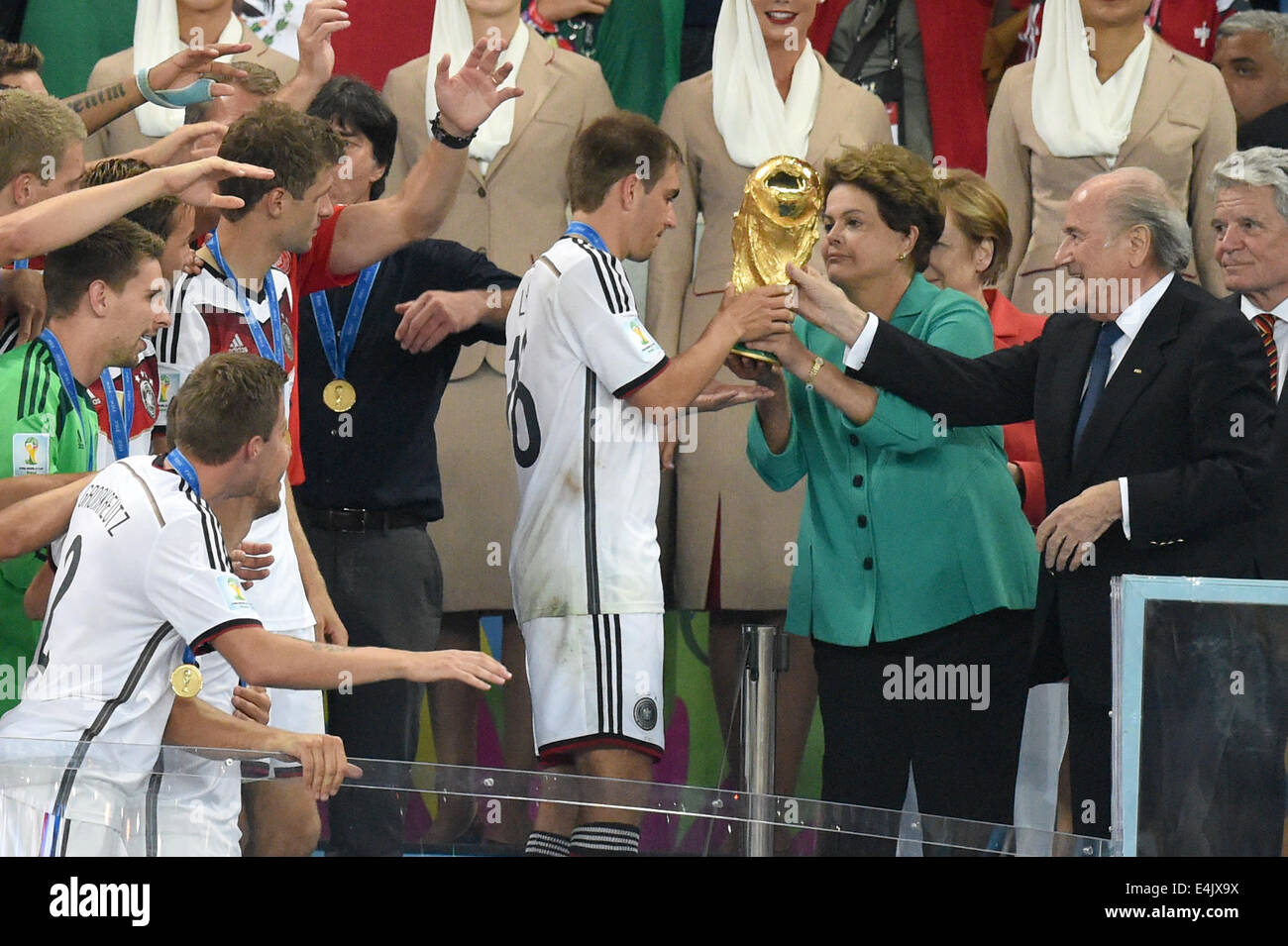 Rio de Janeiro, Brazil. 13th July, 2014. Philipp Lahm (C) of Germany receives the Wolrd Cup trophy from Brazil's President Dilma Rousseff (4-R) next to German Chancellor Angela Merkel (3-R), German FIFA President Sepp Blatter (2-R) and German President Joachim Gauck (R) after the FIFA World Cup 2014 final soccer match between Germany and Argentina at the Estadio do Maracana in Rio de Janeiro, Brazil, 13 July 2014. Photo: Marcus Brandt/dpa/Alamy Live News Stock Photo