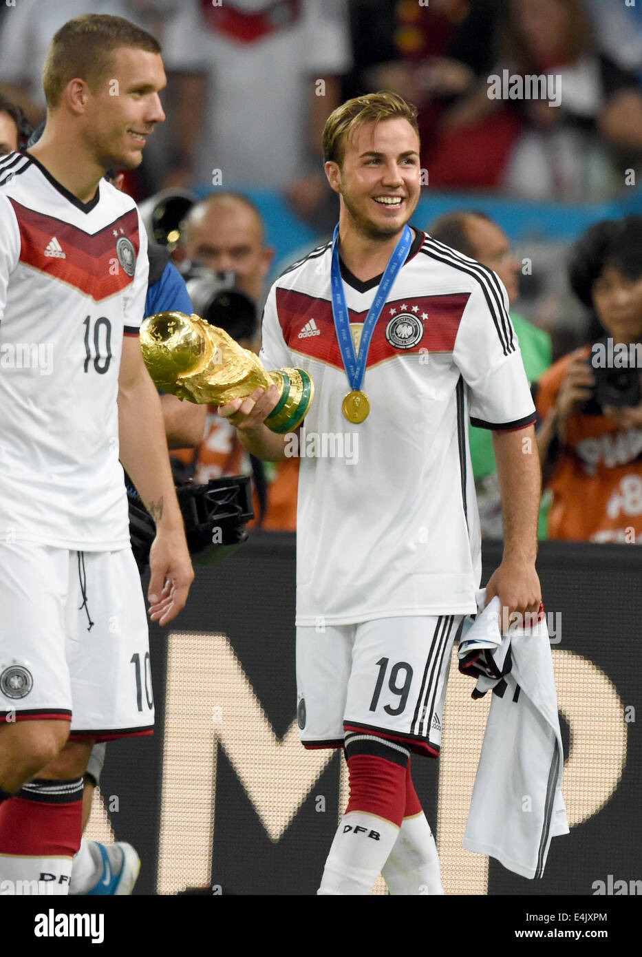 Rio de Janeiro, Brazil. 13th July, 2014. Mario Goetze (R) of Germany holds the World Cup trophy next to Lukas Podolski (L) after winning the FIFA World Cup 2014 final soccer match between Germany and Argentina at the Estadio do Maracana in Rio de Janeiro, Brazil, 13 July 2014. Photo: Marcus Brandt/dpa/Alamy Live News Stock Photo