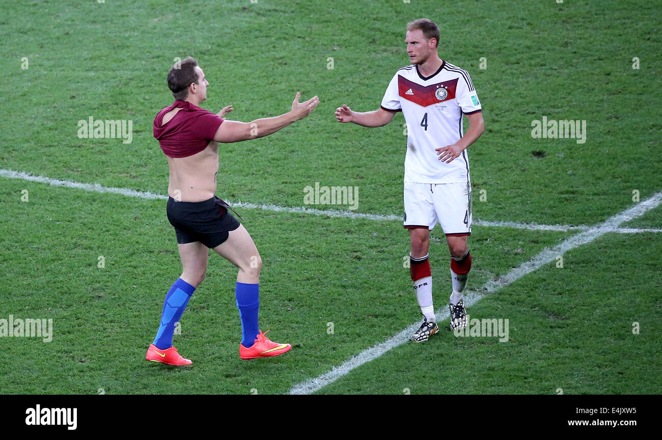 Rio De Janeiro, Brazil. 13th July, 2014. A fan who runs into the field walks towards Germany's Benedikt Howedes during the final match between Germany and Argentina of 2014 FIFA World Cup at the Estadio do Maracana Stadium in Rio de Janeiro, Brazil, on July 13, 2014. Credit:  Li Ming/Xinhua/Alamy Live News Stock Photo