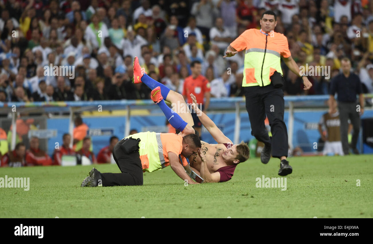 Rio De Janeiro, Brazil. 13th July, 2014. Security members chase a fan who runs into the field during the final match between Germany and Argentina of 2014 FIFA World Cup at the Estadio do Maracana Stadium in Rio de Janeiro, Brazil, on July 13, 2014. Credit:  Yang Lei/Xinhua/Alamy Live News Stock Photo